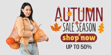 Gri arkaplanda bir sürü balkabağı olan güzel, mutlu bir kadın.