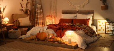 Sonbahar süslemeleri ve akşamları mumları olan şık bir yatak odası.