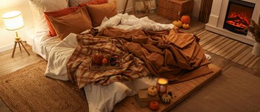 Sonbahar süslemeleri ve akşamları mumları olan şık bir yatak odası.