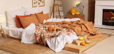 Sonbahar süslemeleri ve şömineli mumları olan şık bir yatak odası.