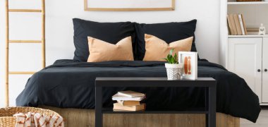 Yatak odasının içinde rahat bir yatakta siyah yatak var.