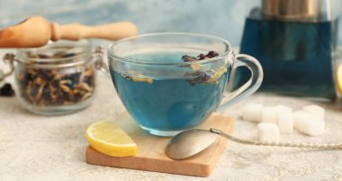 Bir fincan kelebek, bezelye çiçeği çayı ve ahşap tezgah arka planda, yakın plan