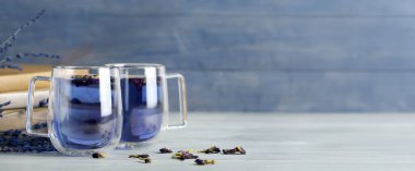 Mavi ahşap arka planda bir fincan kelebek bezelyesi çayı.