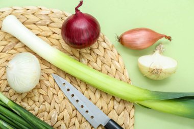 Yeşil arka planda farklı soğan türleri olan hasır paspas, yakın plan.