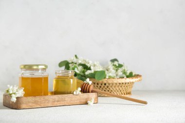 Arkaplanda akasya çiçekleri olan bal kavanozları