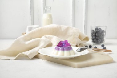 Panna cotta tabağı, ortanca çiçeği ve beyaz masada yabanmersini.