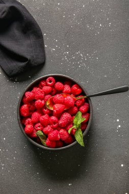 Siyah arka planda taze ahududu ve naneli kase.