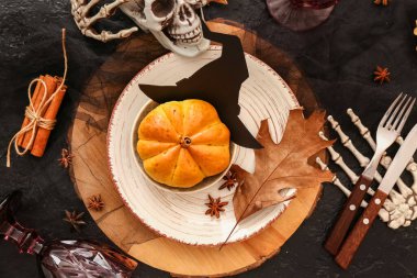 Cadılar Bayramı sofrası, tatlı balkabağı şekilli çörekler ve kafatası koyu arka planda, yakın plan.