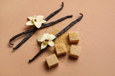 Aromatik vanilya şekeri, çiçekler ve kahverengi arka planda çubuklar