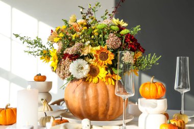 Şenlikli yemek masasında, balkabağında farklı sonbahar çiçeklerinden bir buket.