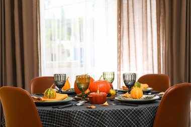 Yemek odasında sonbahar yaprakları ve balkabaklarıyla güzel bir masa, yakın plan.