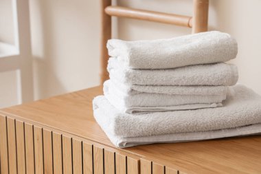 Evdeki ahşap dolapta temiz yumuşak havlular yığını, yakın çekim.