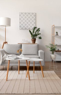 Işıl ışıl oturma odasının içinde rahat bir kanepe, çiçek ve kahve masası var.