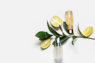 Limonlu kompozisyon, yeşil dal ve beyaz arka planda kozmetik ürünler.