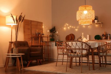 Parlayan lambalar, masa, beyaz tezgah ve sandalyeli modern mutfak.