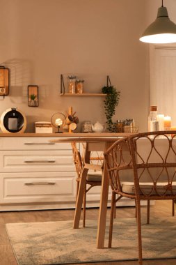 Parlayan lambaları, beyaz tezgahları, masa ve sandalyeleri olan modern mutfak.