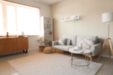 Rahat kanepesi, sehpası ve raf ünitesi olan, bulanık manzaralı, şık bir oturma odası.