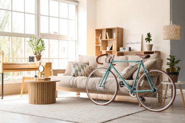 İçinde kanepe, raf ünitesi, sehpa ve bisiklet olan güzel bir oturma odası.