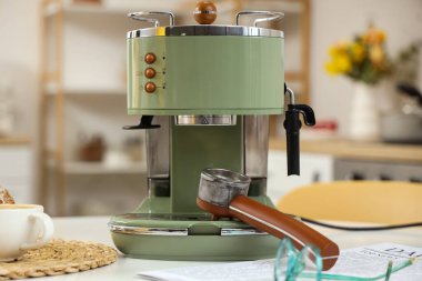 Modern kahve makinesi ve gözlükler mutfaktaki beyaz masada.