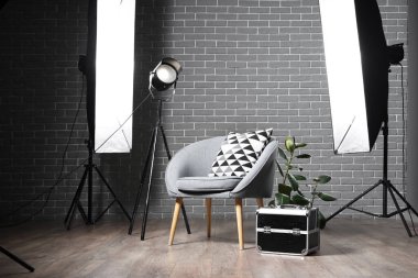 Profesyonel ekipman, ev bitkisi ve koltuk bulunan karanlık fotoğraf stüdyosunun içi