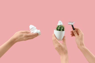 Pembe arka planda jilet, kaktüs ve köpüklü kadın elleri.