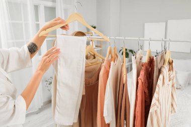 Genç bir kadın yatak odasında elbise topluyor, yakın plan.