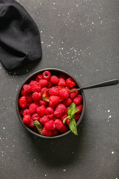 Siyah arka planda taze ahududu ve naneli kase.