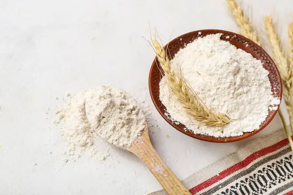 Tahta kase ve kaşık, beyaz arka planda buğday unu.