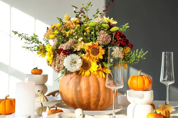 Şenlikli yemek masasında, balkabağında farklı sonbahar çiçeklerinden bir buket.
