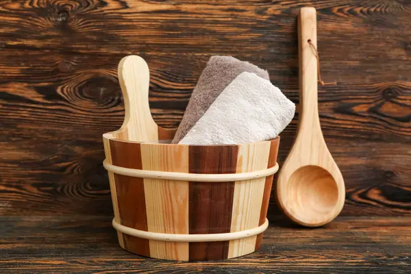 Temiz havlular ve ahşap arka planda sauna için kepçe.