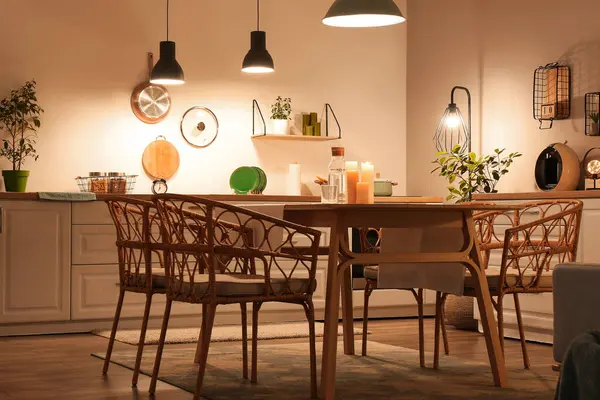 Parlayan lambaları, beyaz tezgahları, sandalyeleri ve akşam yemeği masası olan modern mutfağın içi.