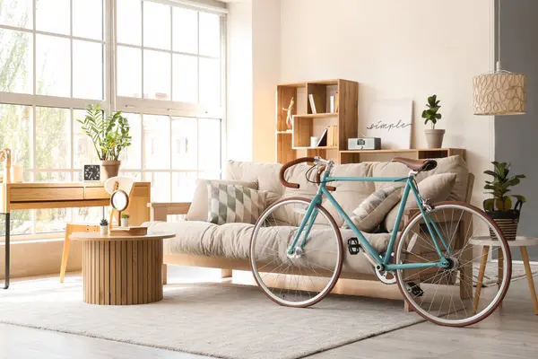 İçinde kanepe, raf ünitesi, sehpa ve bisiklet olan güzel bir oturma odası.