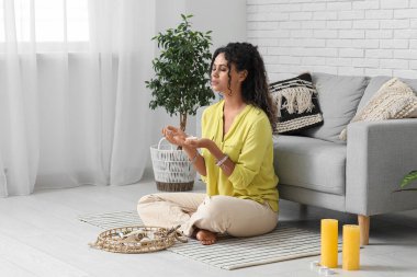 Güzel Afro-Amerikalı kadın şaman evde meditasyon yapıyor.