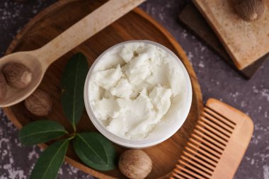 Bir kavanoz Shea yağı, fındık, saç tarağı ve sabun içeren kompozisyon grunge renk arkaplanı, yakın plan