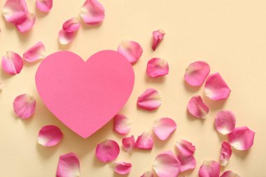 Bej arka planda gül yaprakları olan, kalp şeklinde boş bir kart.