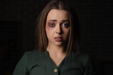 Siyah arka planda yaralı genç bir kadın, yakın plan. Aile içi şiddet kavramı