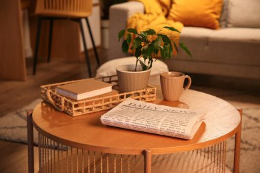 Çay fincanı, kitap ve bitki dolu gazete karanlık oturma odasında.