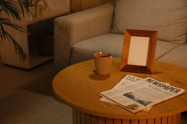 Çay fincanı ve boş çerçeveli gazeteler karanlık oturma odasında, yakın plan.