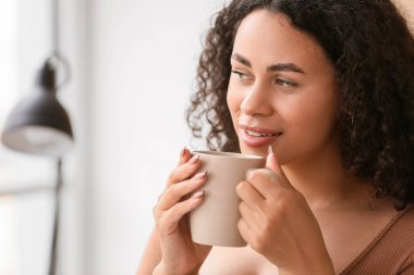 Ofisinde bir fincan sıcak kahveyle güzel bir Afro-Amerikalı iş kadını.