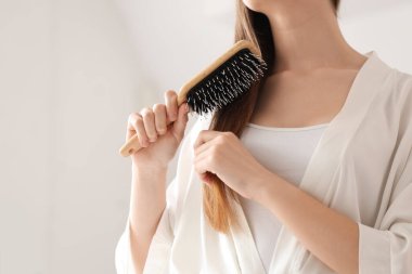 Güzel genç bir kadın banyoda saçını tarıyor.