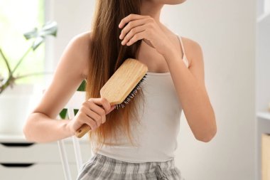 Güzel genç bir kadın banyoda saçını tarıyor.