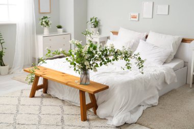 Yatak odasının içi yataklı, yasemin çiçekleri vazolarda, bankta ve tuvalette.