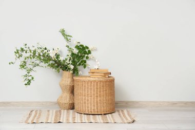 Yasemin çiçeklerinin açtığı bir vazo ve oturma odasındaki gri duvarın yanındaki masada kitaplar.