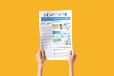 Sarı arka planda gazetesi olan bir kadın.