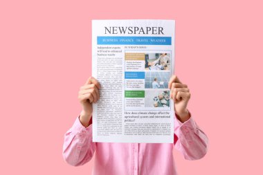 Pembe arka planda gazetesi olan kadın.