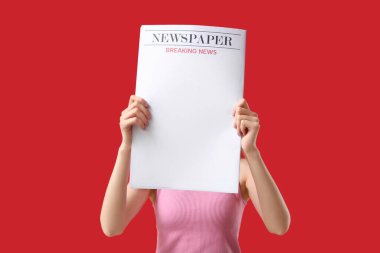 Kırmızı arka planda boş gazetesi olan kadın.