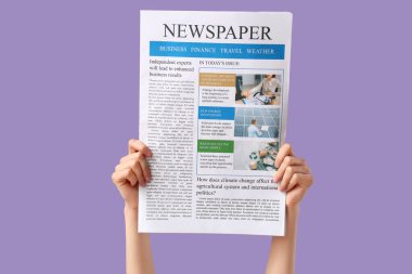 Leylak arka planında gazete olan kadın eller.