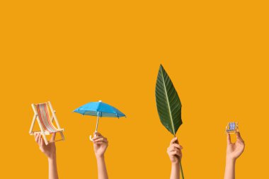 Oyuncak sandalyeli kadın eller, sarı arka planda şemsiye ve palmiye yaprağı. Turizm konsepti