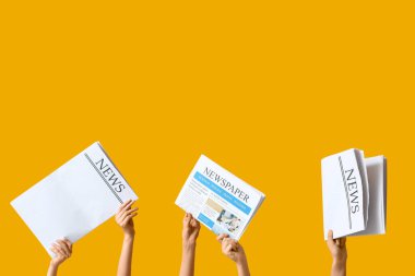 Sarı arka planda gazeteleri olan kadın eller.