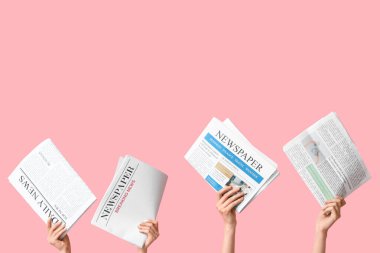 Pembe arka planda gazeteleri olan kadın eller.